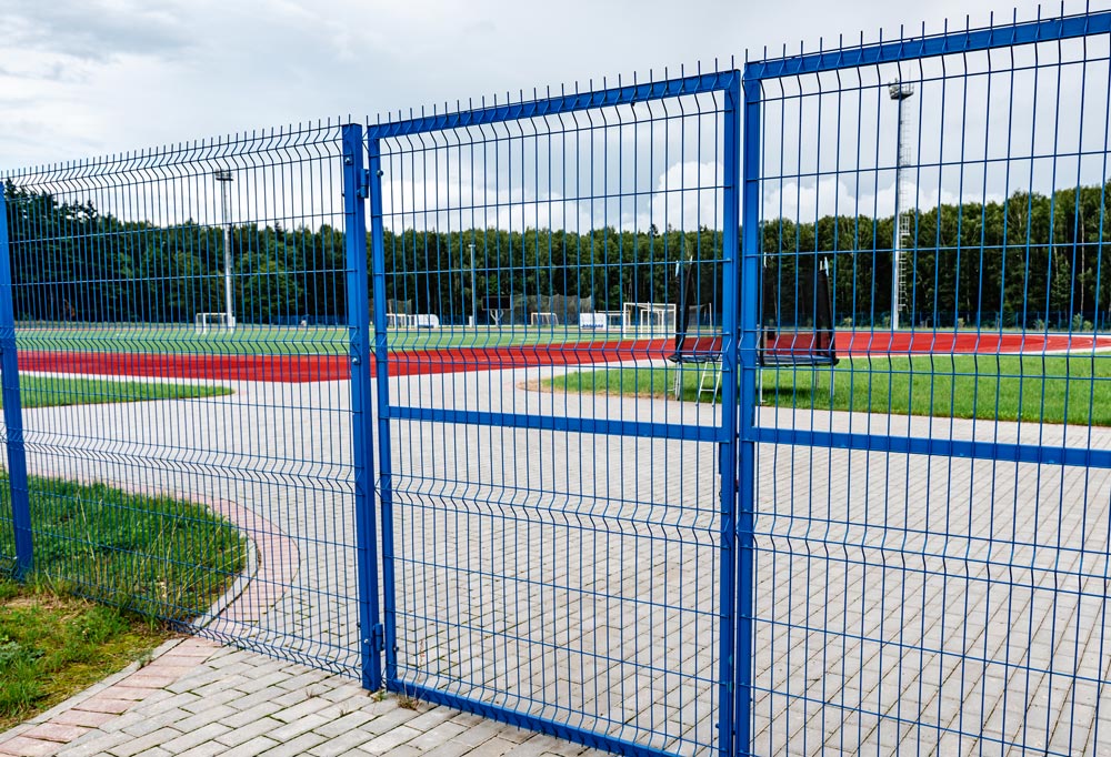 Professionell einbetonierter Eisenzaun mit umlaufenden Pflasterarbeiten auf einem Mehrzweckgelände der Gemeinde – fachgerecht umgesetzt von AS Garten- & Bau.